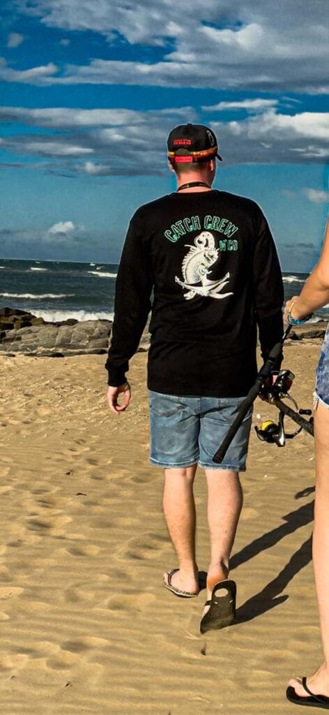 Rear view of male wearing Catch Crew N' Co long sleeve t-shirt walking on the beach