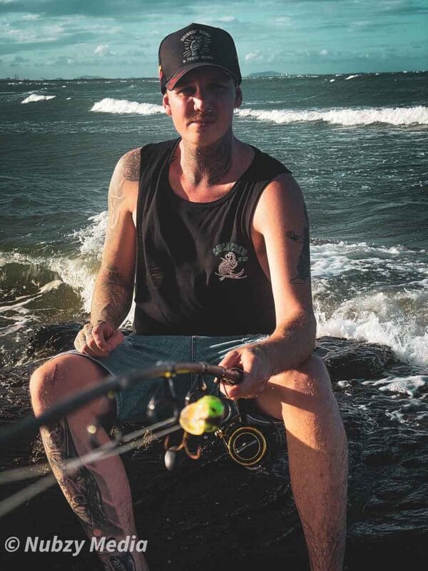 Front view of male wearing Catch Crew N' Co singlet while fishing at the beach