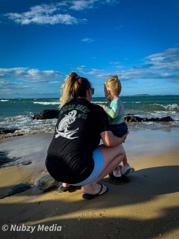 Rear view of female wearing Catch Crew N' Co t-shirt at the beach